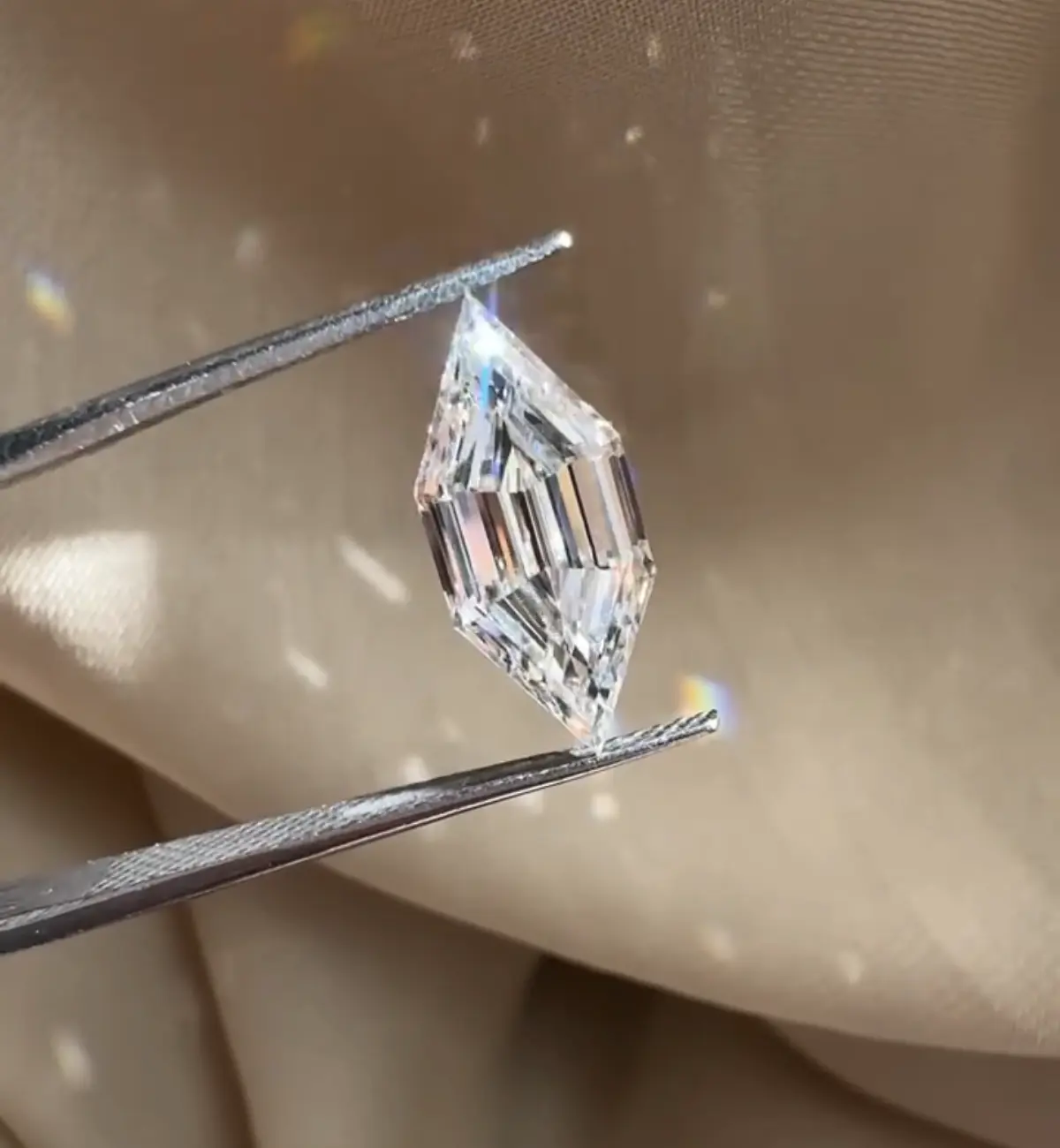 Loose lab-grown oval diamond held in tweezers